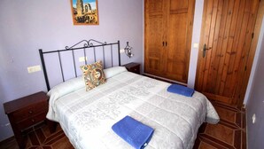 A bedroom with a bed, wooden wardrobe, and a nightstand.