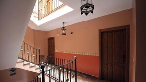 A staircase with a metal railing leading to a landing. There are two doors on the landing, one with a number '2' above it. The walls are painted in a warm color, and there is a skylight above the staircase.