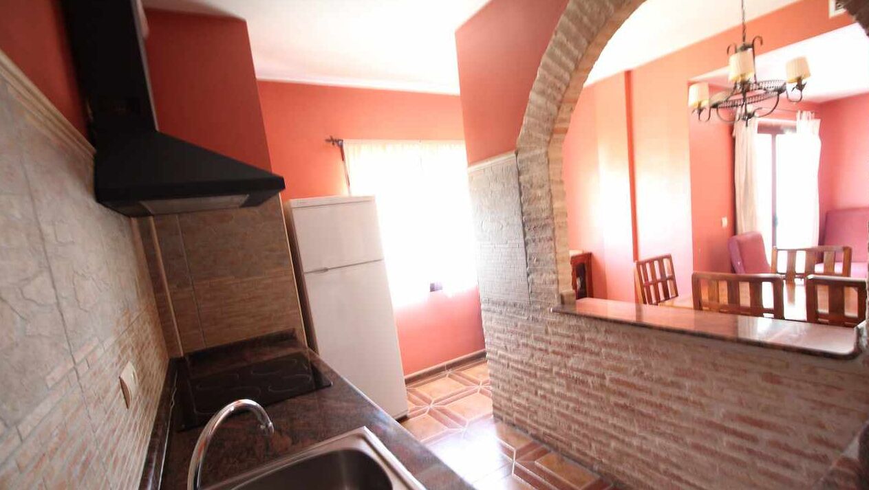 Una cocina con pared de ladrillo, un lavamanos y un refrigerador blanco.