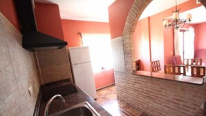 A kitchen with a brick wall, a sink, and a white refrigerator.