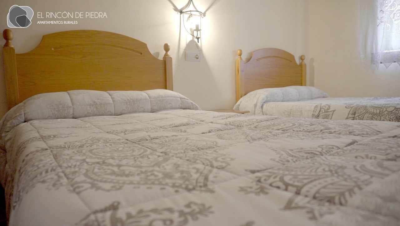 A bedroom with two wooden beds, each with a headboard and a bedside lamp.