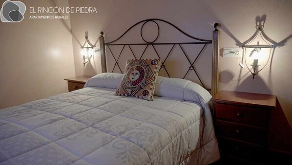 A bedroom with a bed, a nightstand, and wall-mounted lamps. - Self catering El Rincon de Piedra for 4 people (Enguidanos)