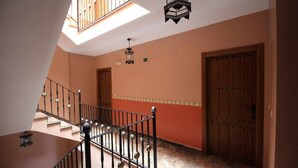 A staircase with a metal railing leading to a landing. There are two doors on the landing, one with a number '2' above it. The walls are painted in a warm color, and there is a skylight above the staircase.