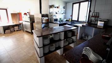 Une cuisine moderne avec des meubles blancs, un plan de travail en granit et un îlot central sur lequel sont empilées des assiettes.
