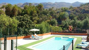 Ein Poolbereich mit Liegestühlen und Blick auf die Berge.