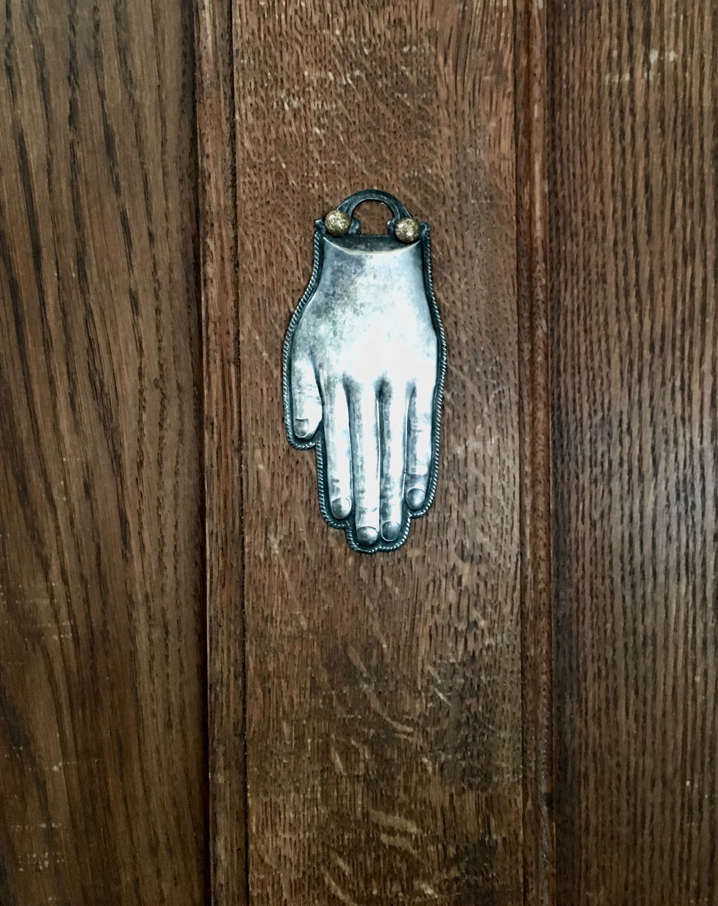 Una porta di legno con una maniglia a forma di mano metallica.