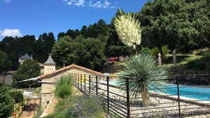 A pool area with a stone deck, surrounded by a fence and various plants. - L'Orangerie • Architect house -Private pool-Nature-Village view-Calm-Rivers.  (Joannas)