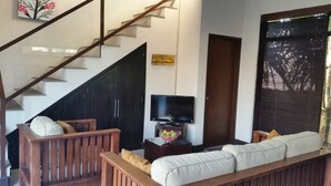 Una sala de estar con una escalera, un televisor y un sofá.