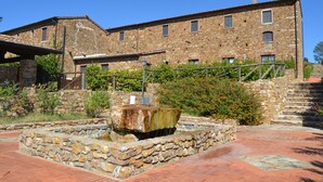 Ein Steinhaus mit Innenhof, Brunnen und einer Treppe, die zum Eingang führt.