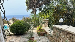 A stone-paved patio with potted plants, a small tree, and a stone wall. - 2 bedroom self contained furnished flat with pool, 5 mins walk to town & beach. (Kalkan)