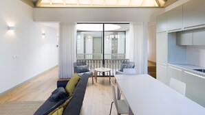 A modern living room with a large window, a dining area, and a kitchen. - Yellow House - The Skylight (Porto)
