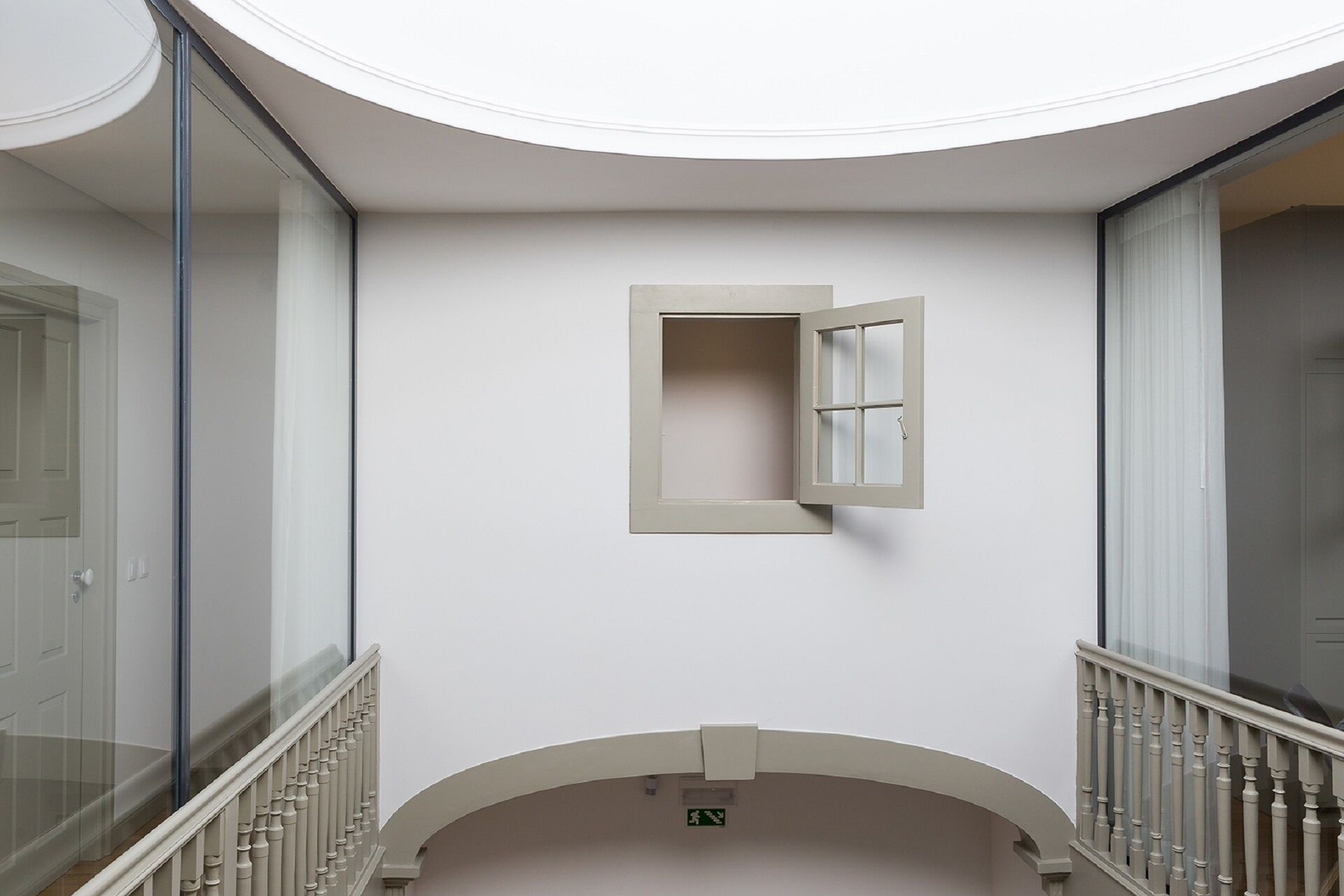 Ein Korridor mit einem kleinen Fenster, einer Glastür und einer Treppe.