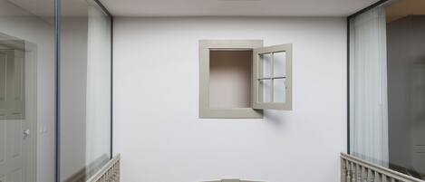 Ein Korridor mit einem kleinen Fenster, einer Glastür und einer Treppe.