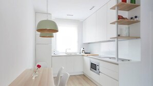 A modern kitchen with white cabinetry, a wooden countertop, and a built-in oven. There is a dining table with chairs and a pendant light above it. - Nice and cozy apartment in Pamplona center! (Pamplona/Iruña)