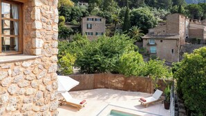 A stone building with a pool, a lounge chair, and a view of a mountainous area. - SA VOLTA DE CA NóLIVER DEIA Villa with New Pool & Sea and Mountain Views (DEIA)