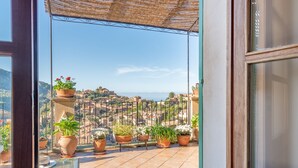 A balcony with potted plants and a view of a hillside town. - SA VOLTA DE CA NóLIVER DEIA Villa with New Pool & Sea and Mountain Views (DEIA)