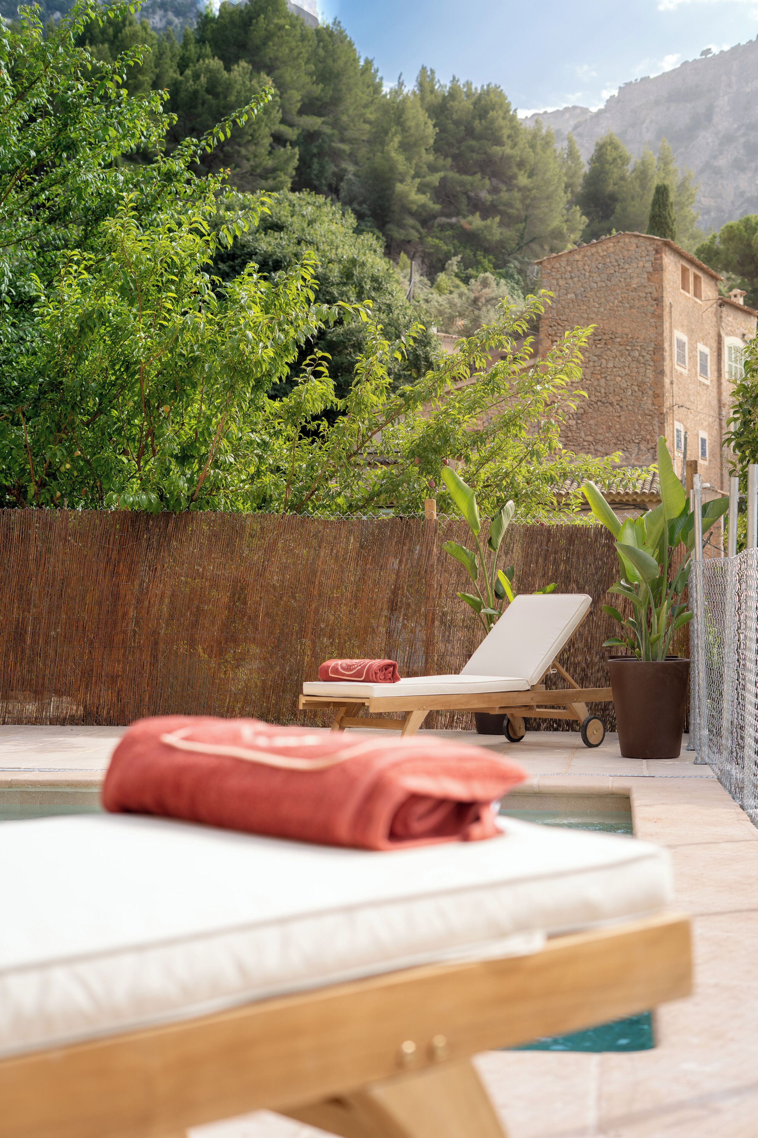 A sun lounger with a towel, a potted plant, and a view of a mountainous landscape.
