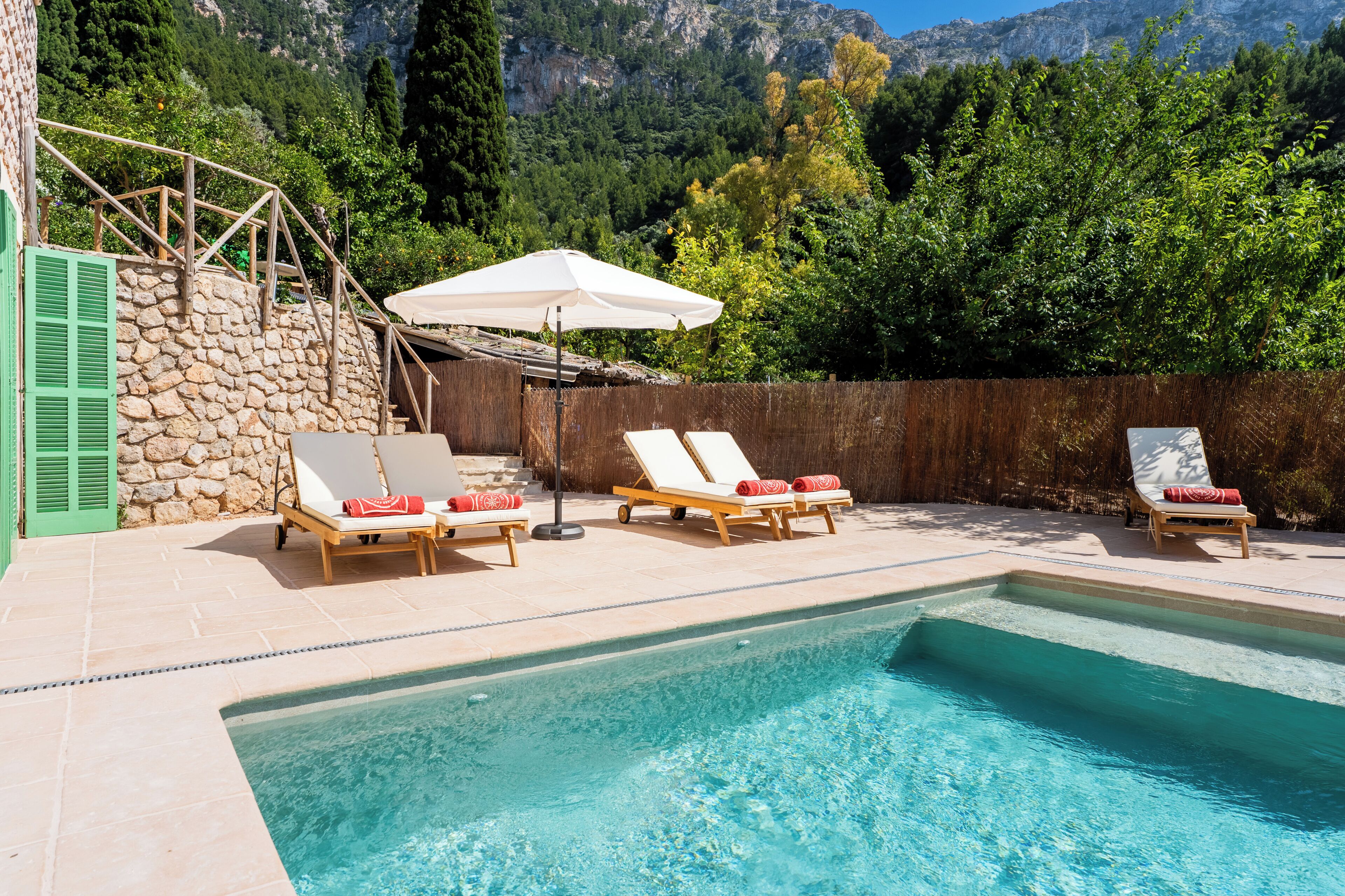 A swimming pool with lounge chairs and a stone wall.