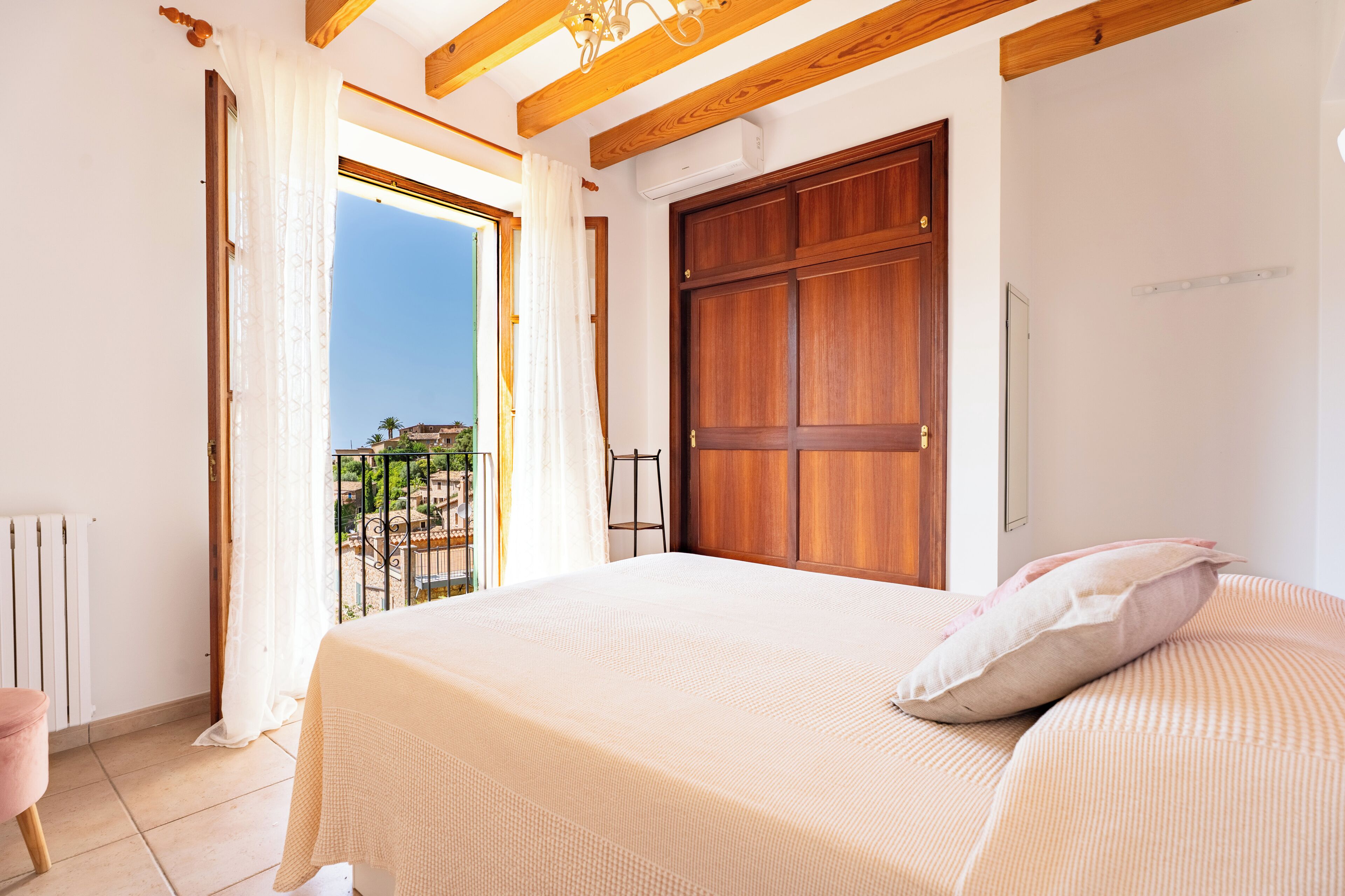 A bedroom with a bed, a wooden door, and a window with curtains.