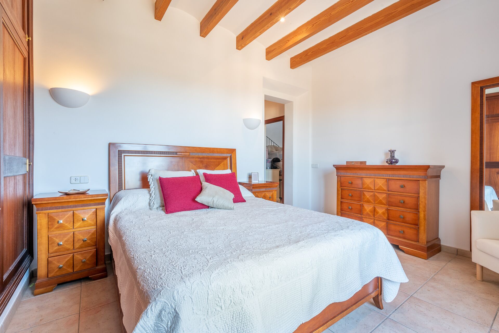 Una camera da letto con un letto in legno, un comodino, una cassettiera e uno specchio.