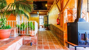 A wooden interior with a tiled floor, a black stove, and potted plants.