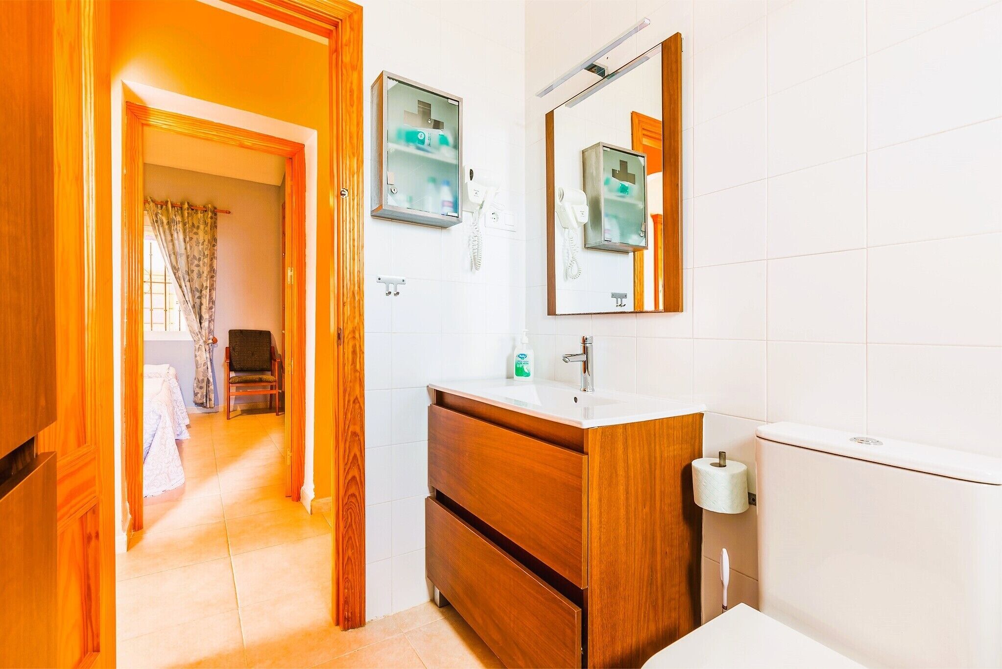 A bathroom with a wooden vanity, a mirror, a toilet, and a shower area.