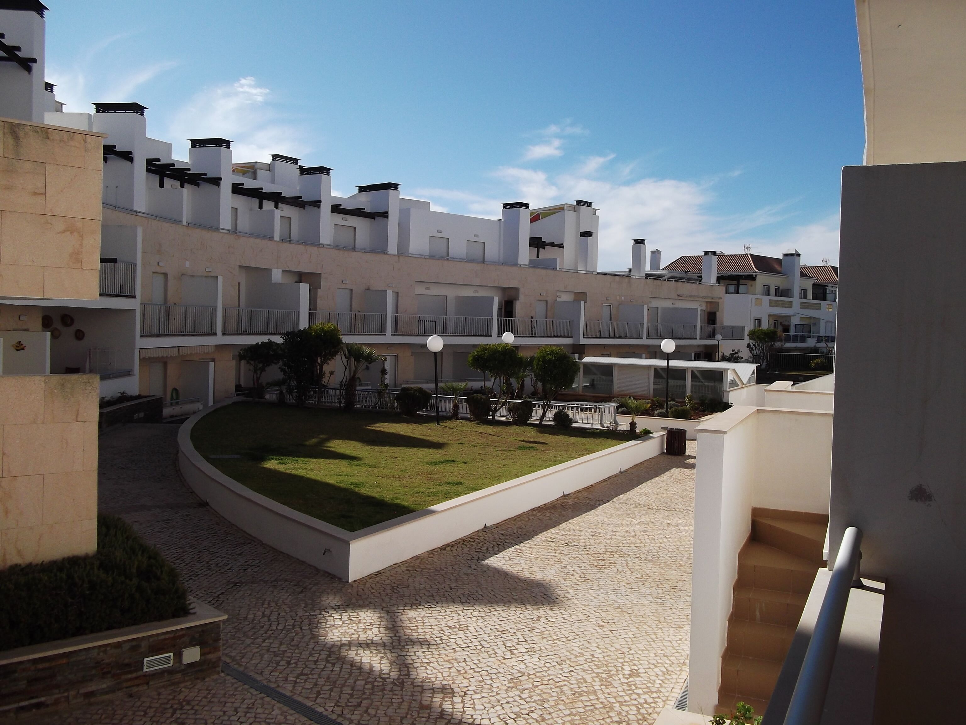 A courtyard with a paved area, surrounded by multi-story buildings with balconies and windows.