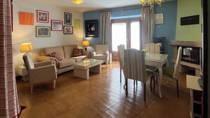 A living room with a sofa, armchairs, a coffee table, and a dining area with a table and chairs. - The Feng Shui House Perseverance for 4 people (Aldehuela)