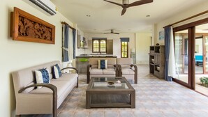 A spacious living area with a sofa, armchairs, a coffee table, and a ceiling fan. - Deluxe 3 bed room pool villa in beach resort Idyllic Samui (Ko Samui)