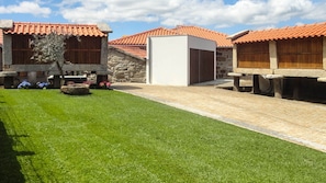 A courtyard with a well-maintained lawn, stone walls, and buildings with red-tiled roofs.