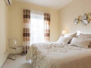 Ein Hotelzimmer mit Bett, Stuhl, einem Fenster mit Vorhängen und einer Wanddekoration.