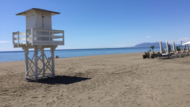 A lifeguard tower on a sandy beach with a clear view of the ocean and distant mountains. - Beautiful apartment near the beach (Rincón de la Victoria)