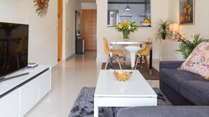 A modern living room with a flat-screen TV, a white coffee table, a sofa, and a dining area with a table and chairs. - Beautiful apartment near the beach (Rincón de la Victoria)