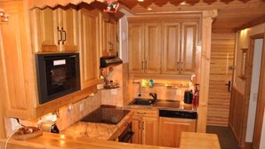 A compact kitchen with wooden cabinets, a built-in microwave, a stove, and a sink.
