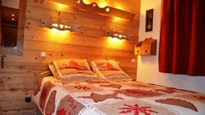 A cozy wooden cabin room with a bed, a small wooden cabinet, and a wall-mounted light fixture.