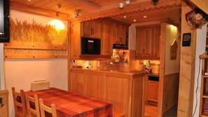 A cozy kitchen with wooden cabinets, a central island, and a dining table with chairs.