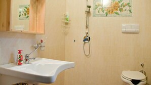 Een badkamer met een wastafel, toilet, douche en een spiegel.