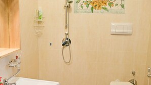 Een badkamer met een wastafel, toilet, douche en een decoratieve betegelde muur.
