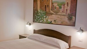 Een slaapkamer met een bed, twee nachtkastjes en een schilderij van een gebouw en bloemen aan de muur.