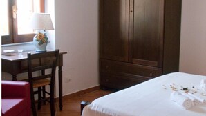 Een hotelkamer met een bed, een bureau met lamp, een stoel en een kledingkast.