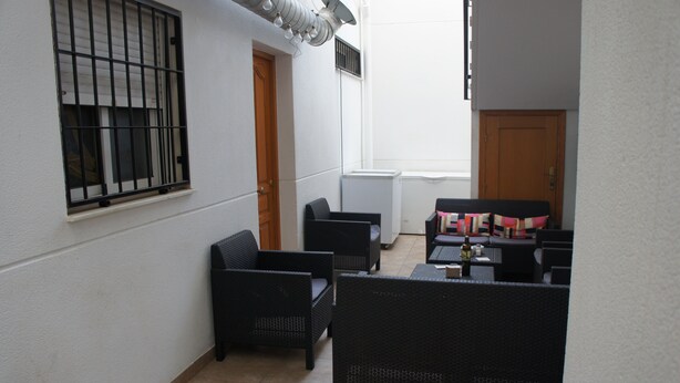 A small, enclosed patio area with wicker furniture and a sofa, a window with bars, and a door. - Comfortable apartment within walking distance of Almería (Alhama de Almería)