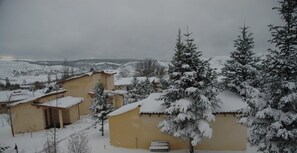 Un village enneigé, avec des bâtiments traditionnels et un banc au premier plan.