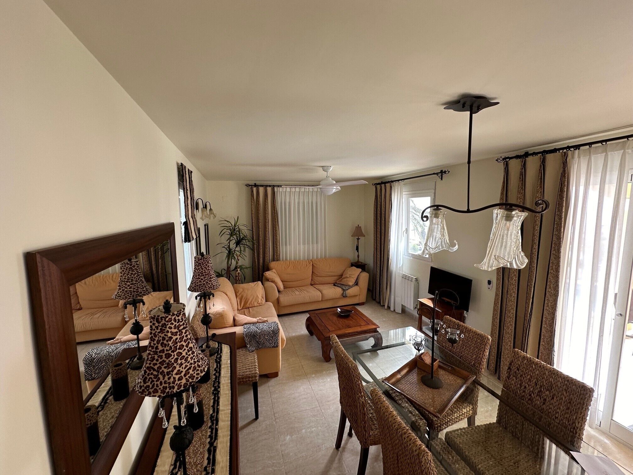 A living room with a sofa, a glass coffee table, and patterned chairs.