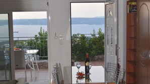 A modern dining area with a view of the sea, a dining table with chairs, and a wine bottle. - Bay View Villa I in Crete with private swimming pool and modern convenient (Chania)