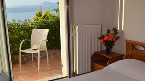 A bedroom with a bed, a chair, a radiator, and a view of the outdoors. - Bay View Villa I in Crete with private swimming pool and modern convenient (Chania)