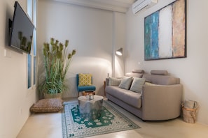 A living room with a sofa, a coffee table, a lamp, and a painting on the wall.