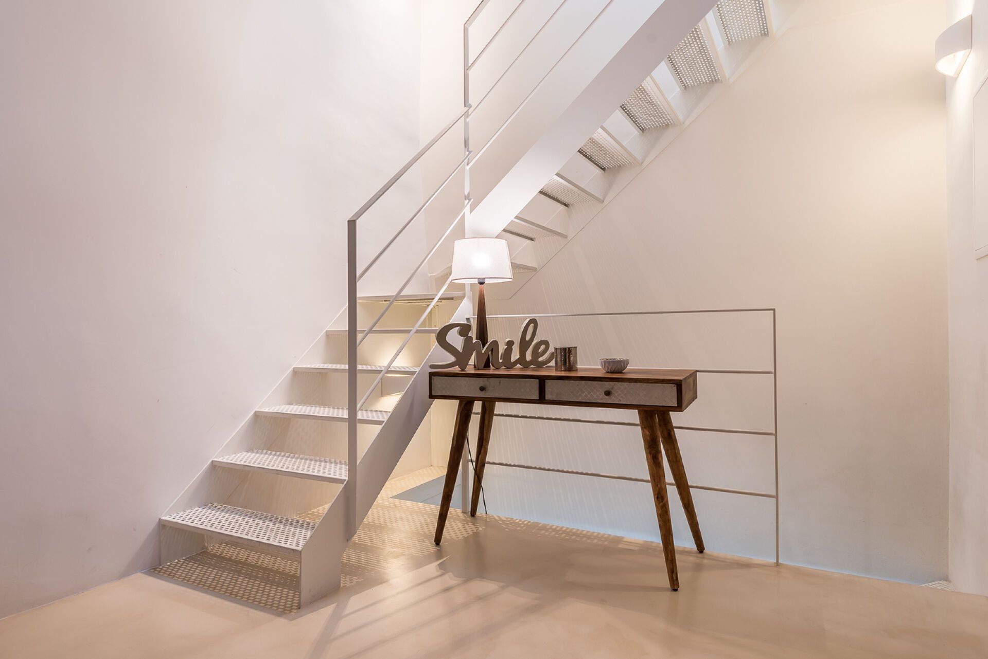 Eine Treppe mit modernem Design, ein Schreibtisch mit Lampe und ein dekoratives Schild.