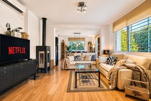 A modern living room with a fireplace, a sofa, a coffee table, and a television displaying 'NETFLIX'. - VillaSense Luxury | Golf, Pool & Nature | Seville (Guillena)