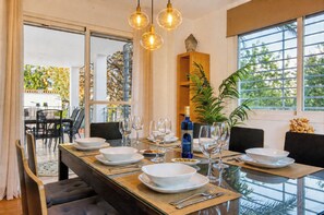 A dining area with a glass table set for a meal, surrounded by chairs, with a Buddha statue and a plant in the background. - Magnificent Villa with large pool and garden with 100% private views in Seville (Guillena)