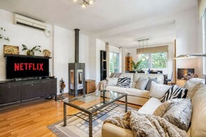 A modern living room with a fireplace, a sofa, a coffee table, and a television displaying 'NETFLIX'. - Magnificent Villa with large pool and garden with 100% private views in Seville (Guillena)